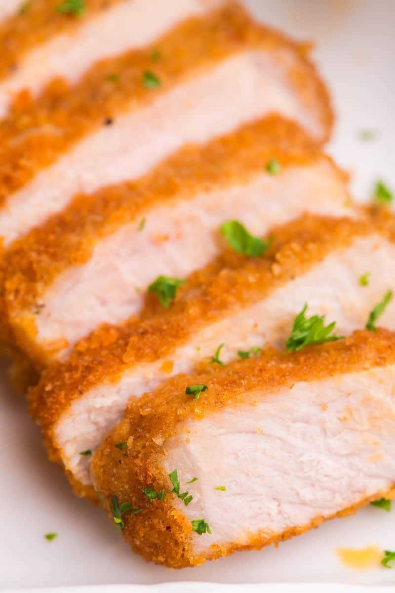 Tender, sliced, air fried pork chops on a white platter.