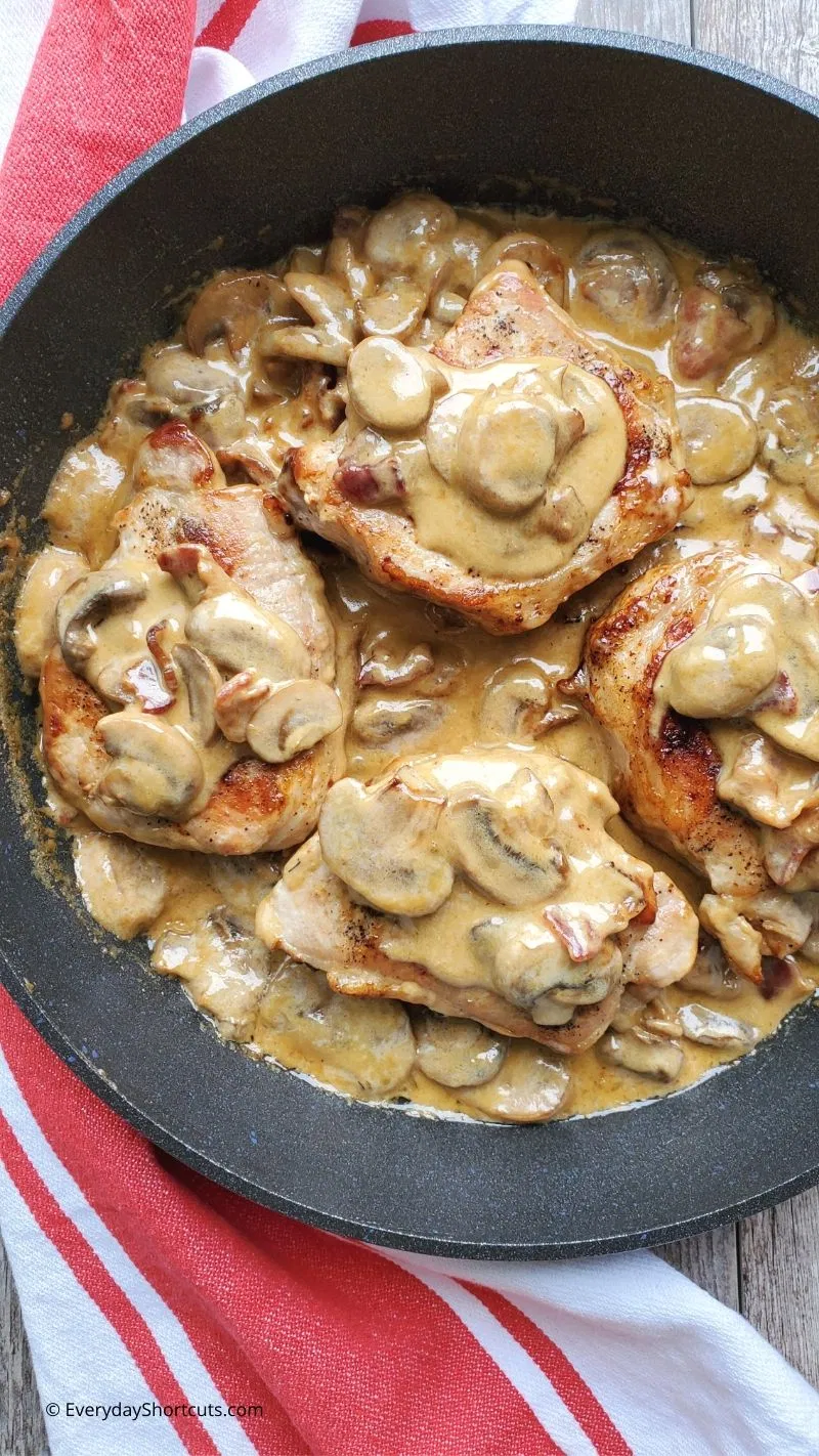 Bacon mushroom pork chops in a pan.