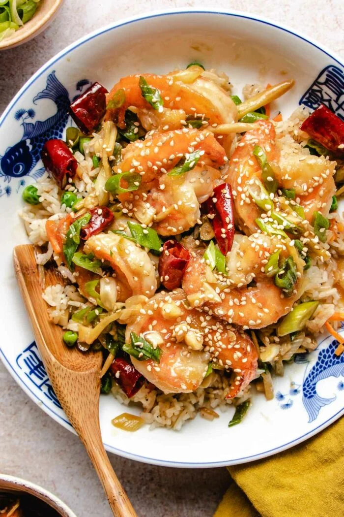 General tso chicken with peppers scallions on a decorative white plate.