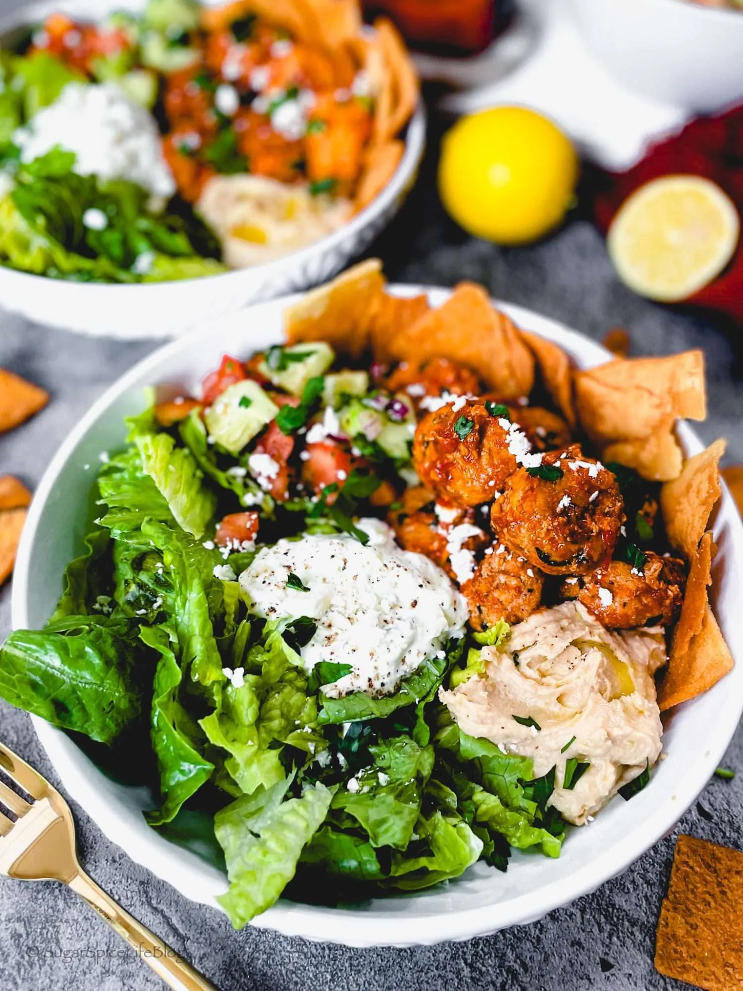 Harissa chicken meatballs with lettuce seasoned veggies, pita chips, and garlicky feta tzatziki sauce.