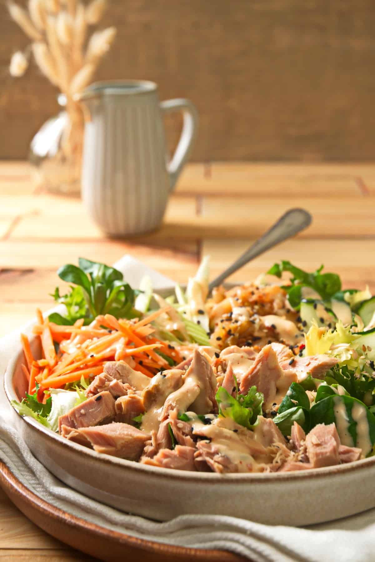 Salad with canned tuna, julienned carrots, lettuce, dressing, etc., on a plate.