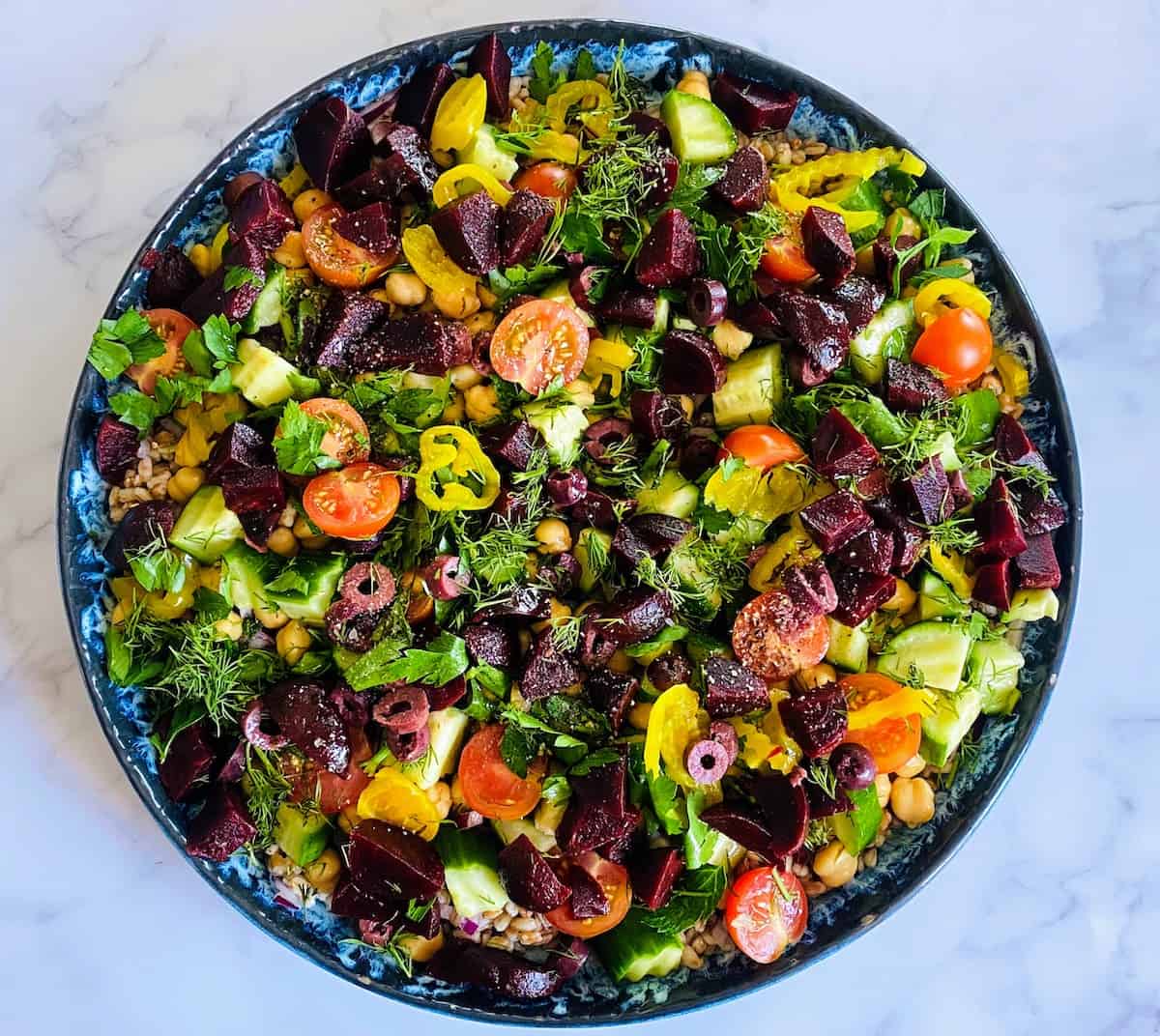 Mediterranean salad with a variety of vegetables in a blue bowl.