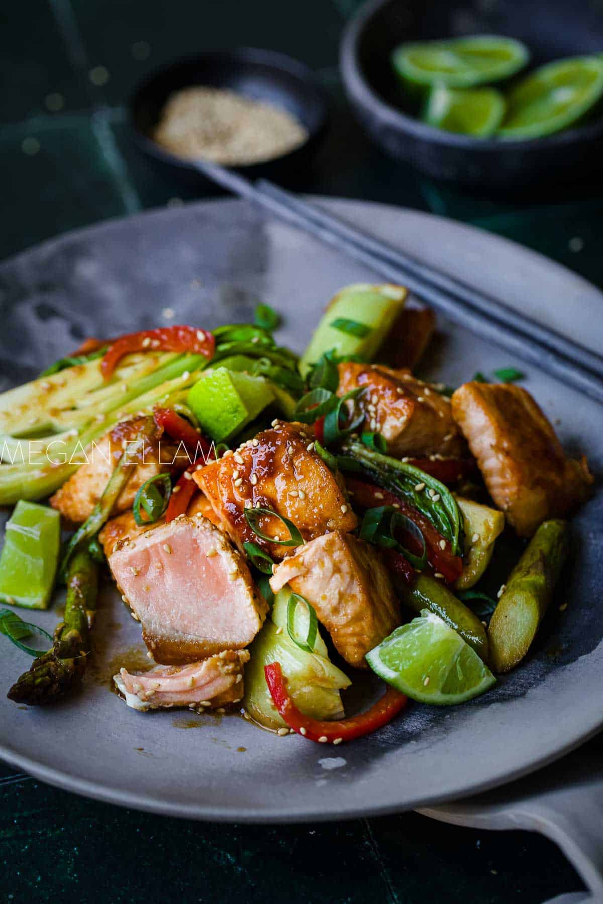 Salmon and vegetable stir-fry on a dark plate.