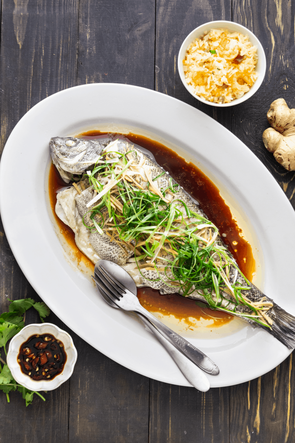 Cantonese steamed fish with sauce on a white platter.