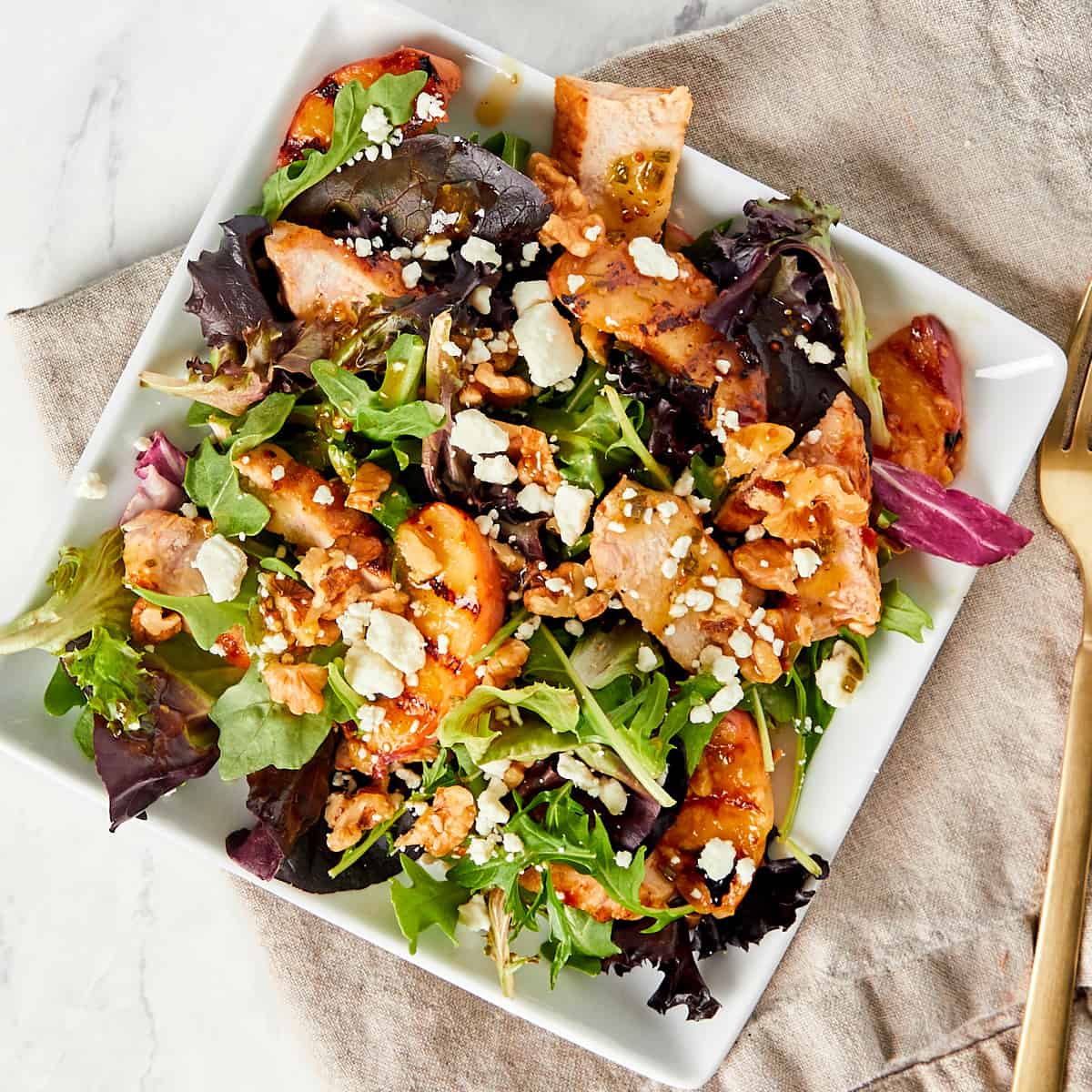 Grilled peach and pork chops and goat cheese with walnut on a bed of lettuce