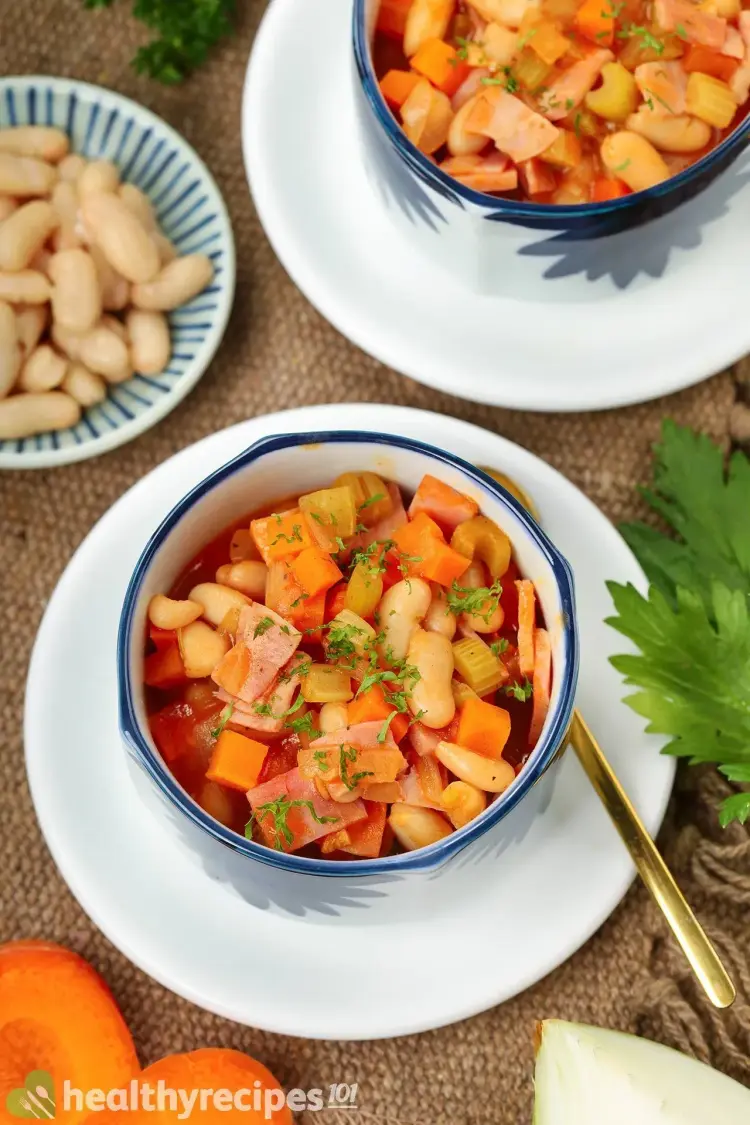 Spam and bean soup in bowls on a white plate with a golden spoon.