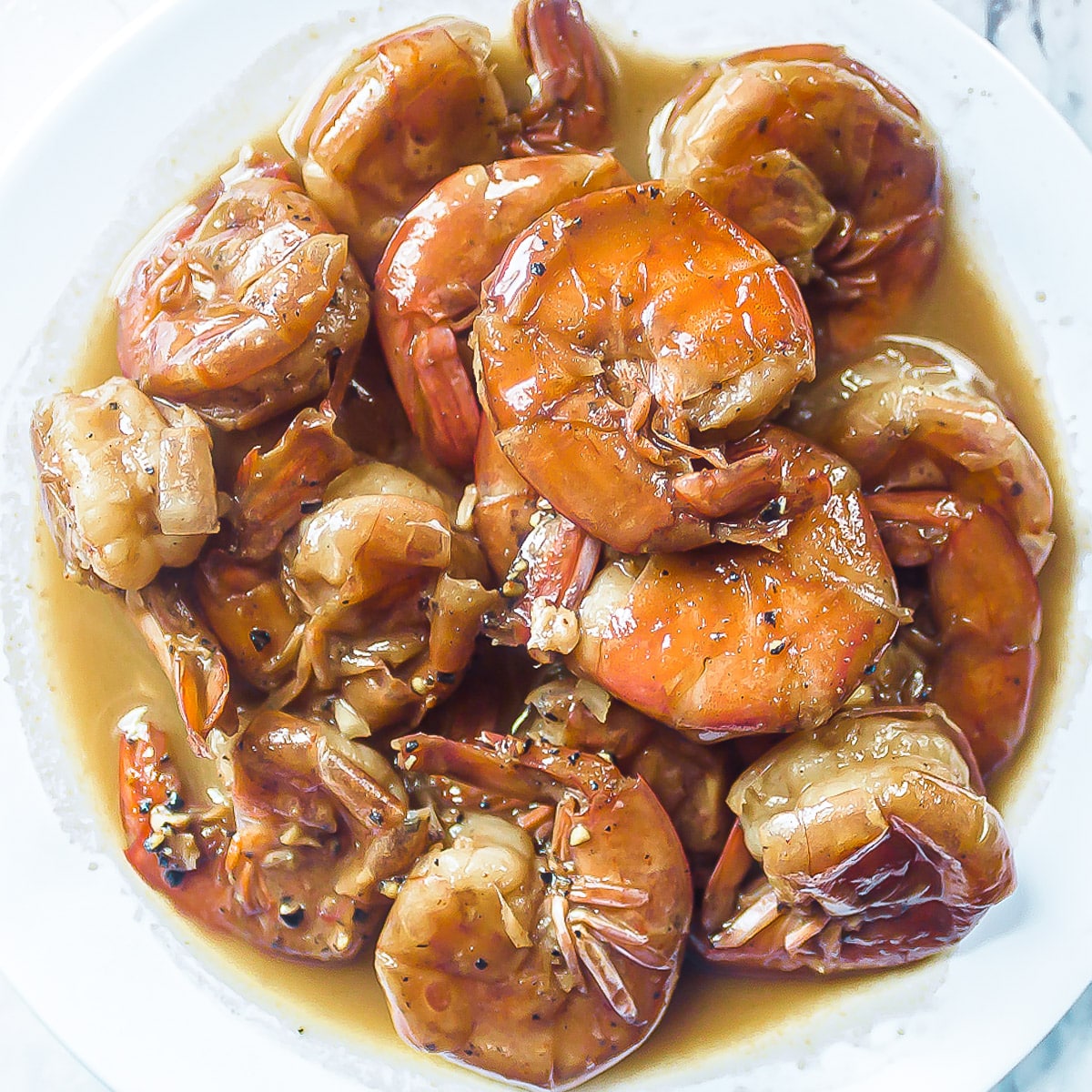 New Orleans style bbq shrimp in a white bowl.