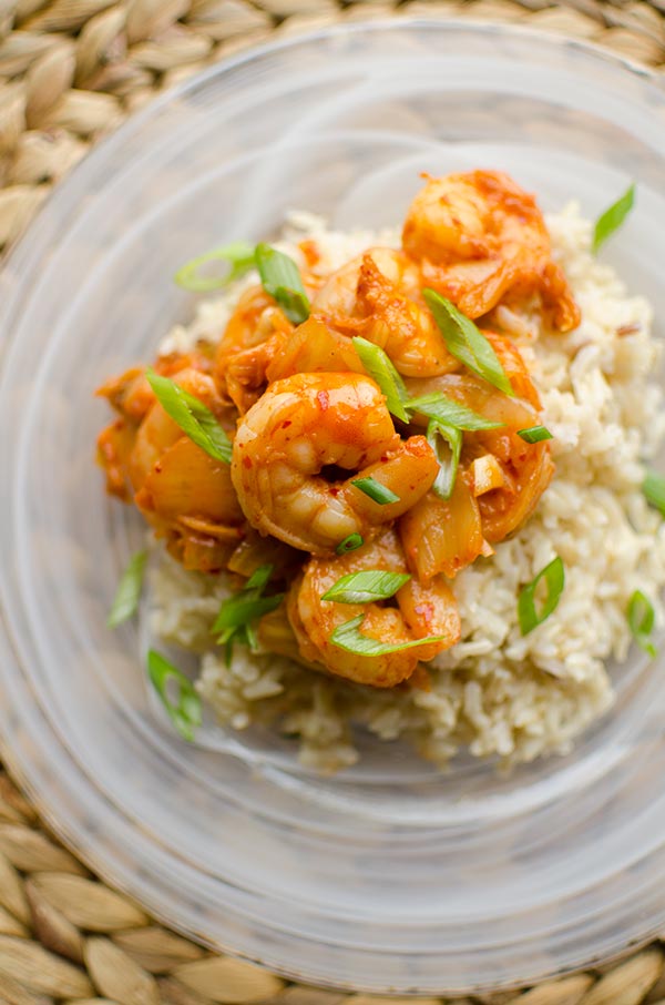 Shrimp and kimchi over rice on a plate.