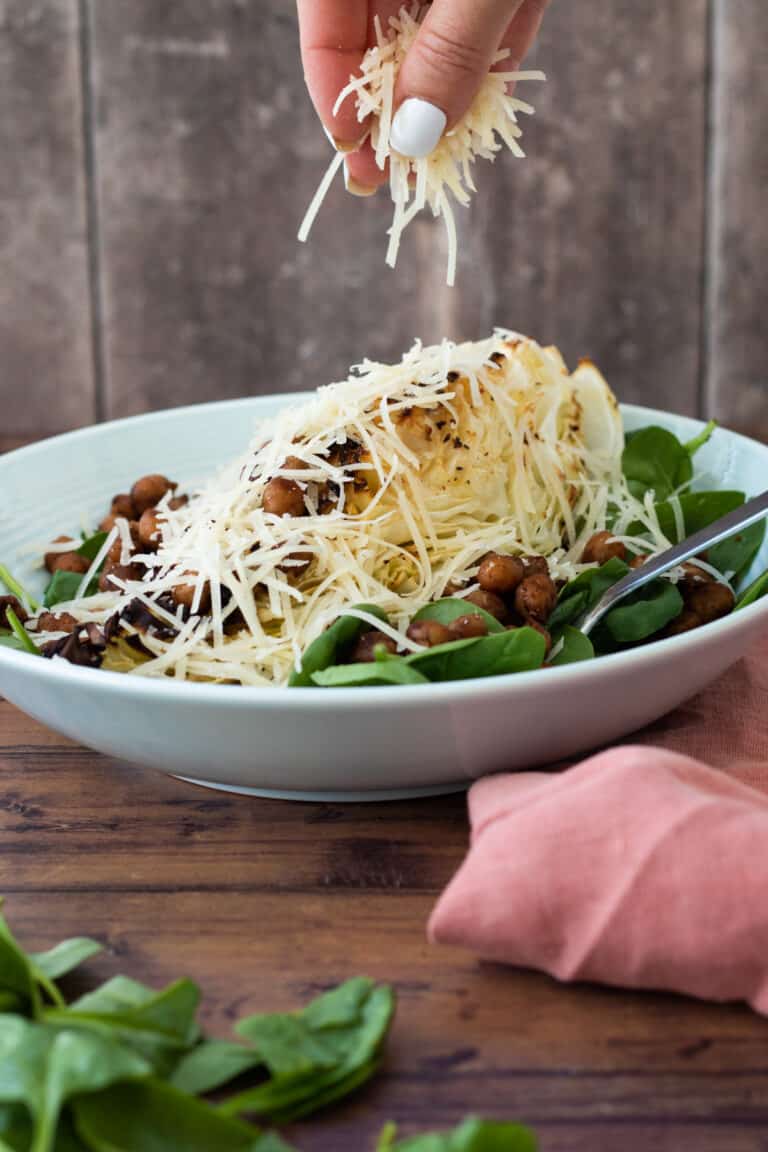 Sweetheart cabbage with chickpeas, baby spinach, cheese, with a fork in a bowl.