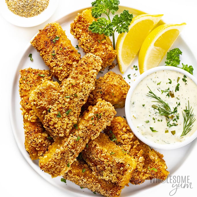 Keto fish sticks with lemon wedges and tartar sauce.