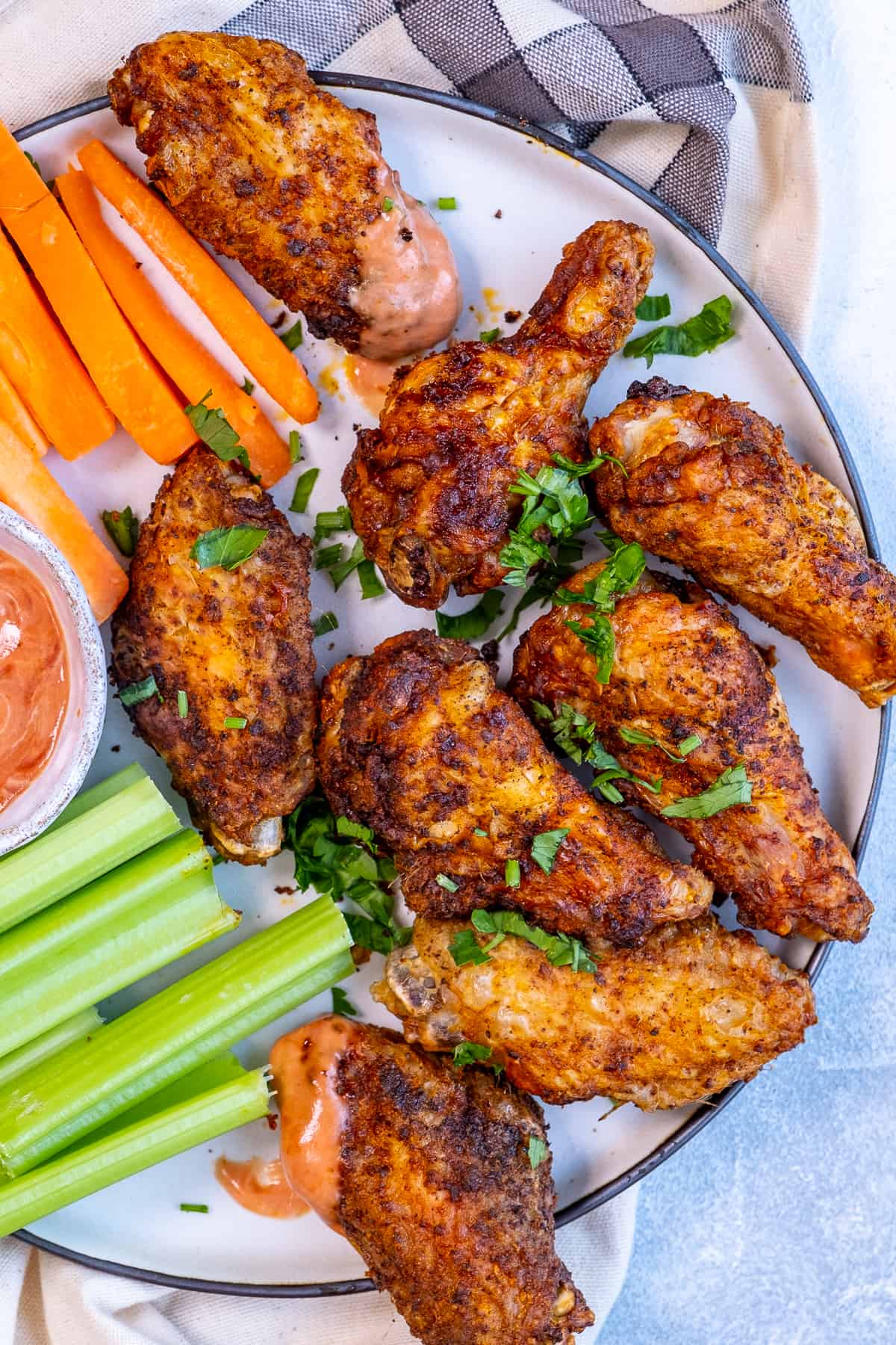 Chicken wings with carrots, celery, and herbs on a plate.