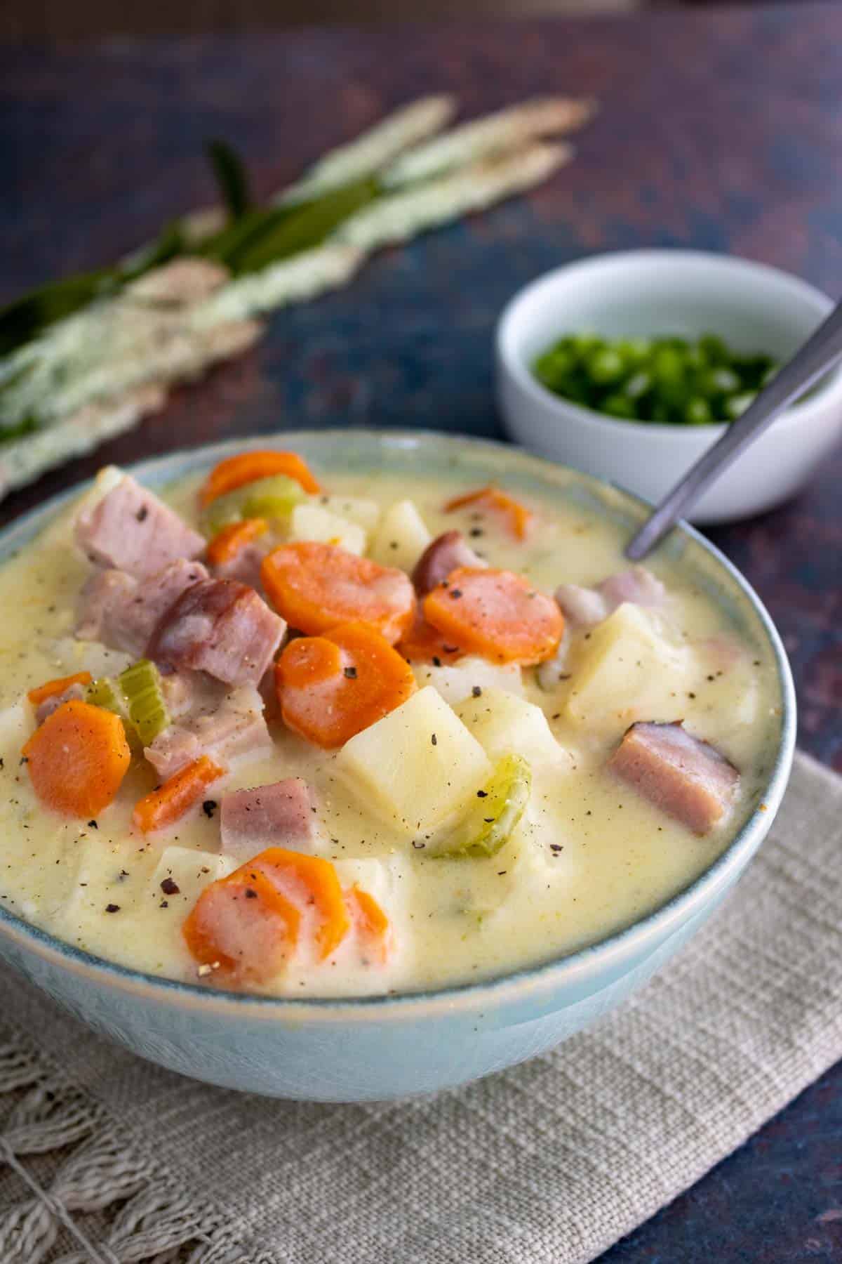 Ham and potato crockpot soup in a bowl with a spoon.