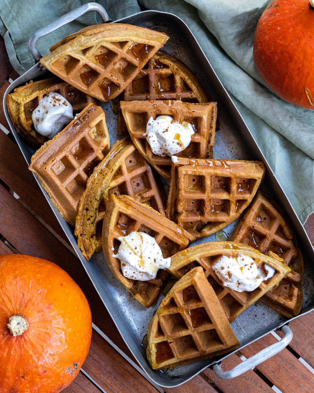 Tray of pumpkin waffles with pumpkins in the background.