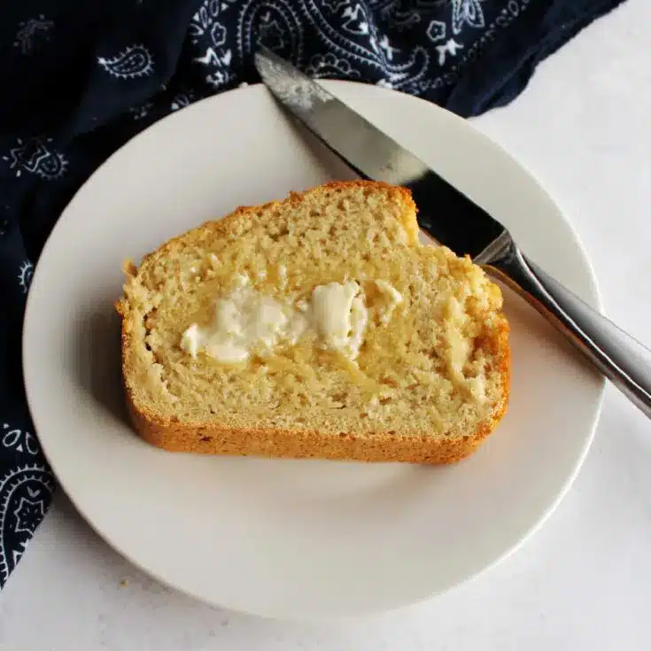 Buttered slice of beer bread on a white plate.