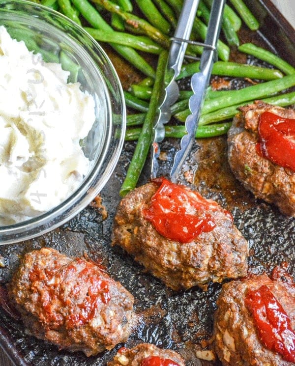 Miniature meatloaf, mashed potatoes, and green beans on a sheet pan.