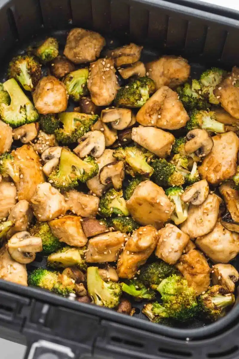 Air fryer chicken and broccoli in an air fryer basket.