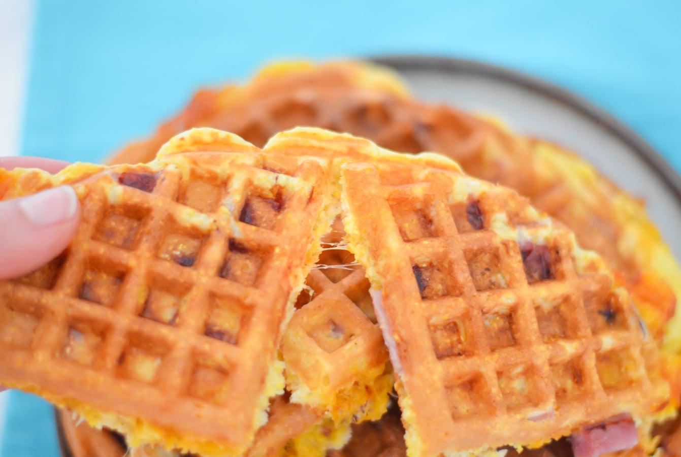 Hand holding am and cheese waffles.