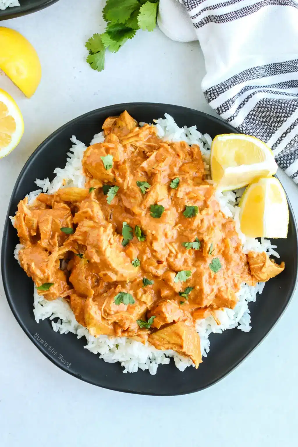 Instant pot chicken tikka masala with lemon on a black plate.