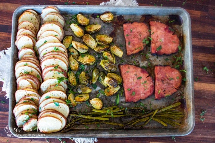 Ham steak, Brussels sprouts, asparagus, and potatoes on a sheet pan.