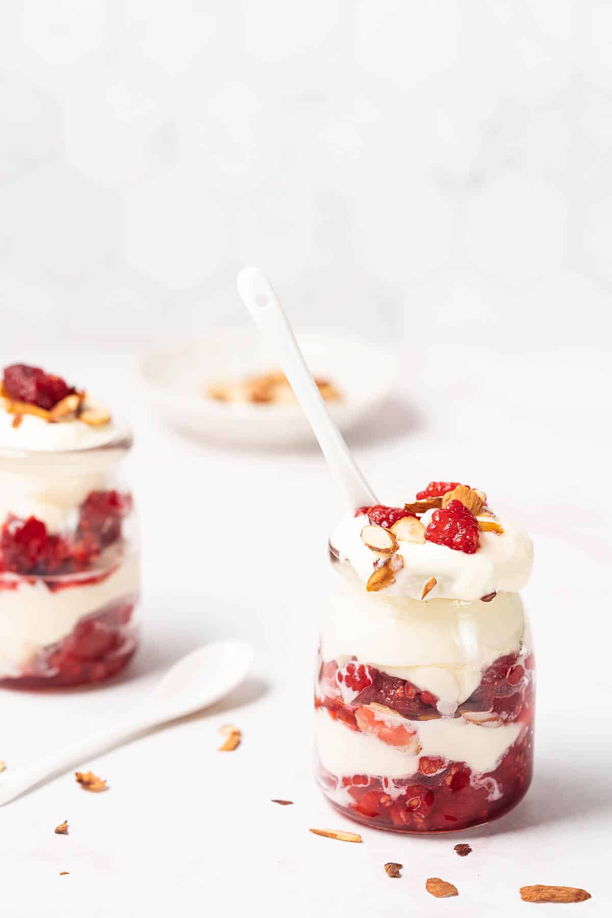 Two servings of individual raspberry almond ricotta parfaits.
