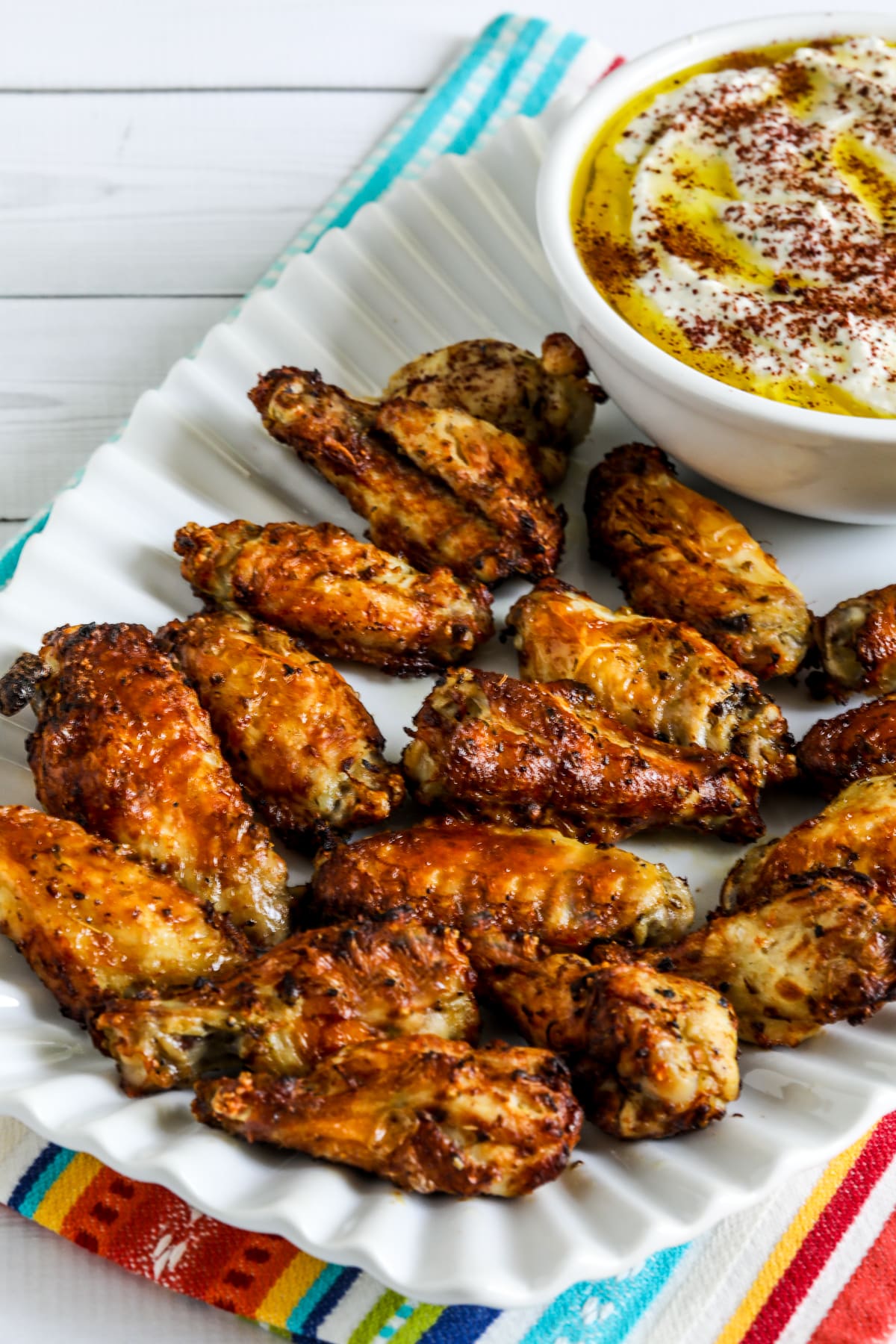 Greek air fryer chicken wings on a serving plate with whipped feta sumac dipping sauce.