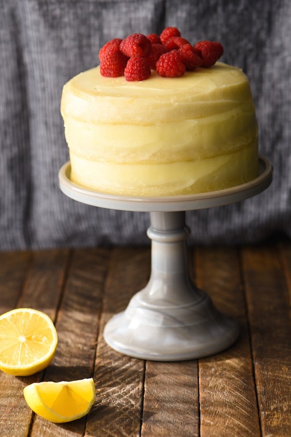 Lemon and raspberry cake for two on a gray cake stand.