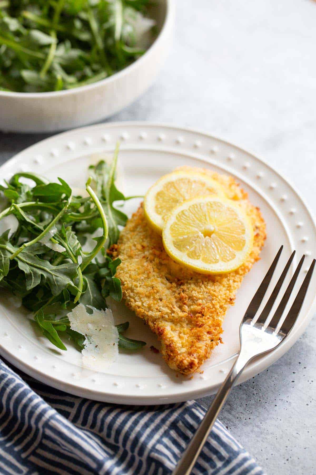 Air fryer panko chicken with lemon and lettuce on a plate.