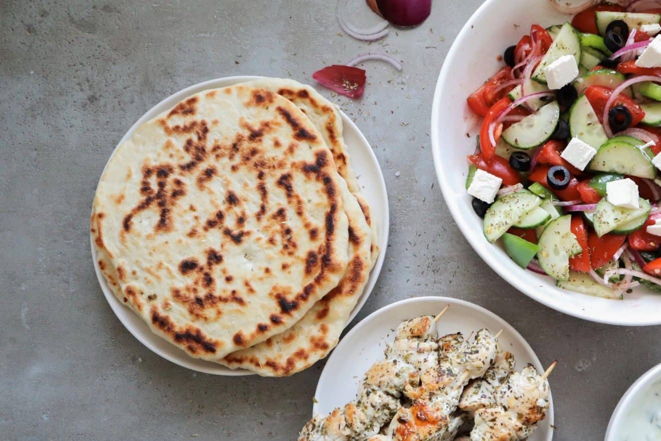 Greek pita bread, salad, and skewered chicken.