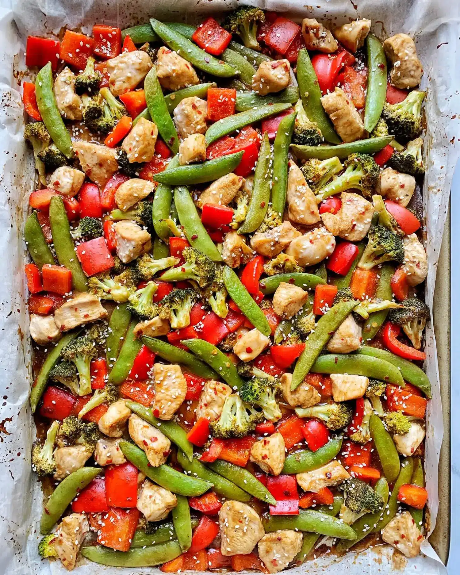 Kung Pao chicken on a parchment paper lined sheet pan.