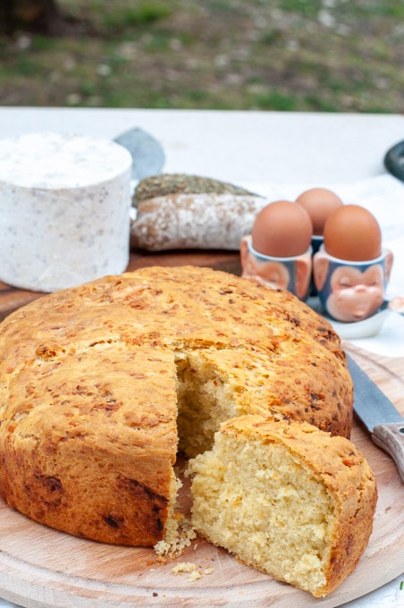 Traditional Italian cheese bread on a cutting board with ingredients in the background.