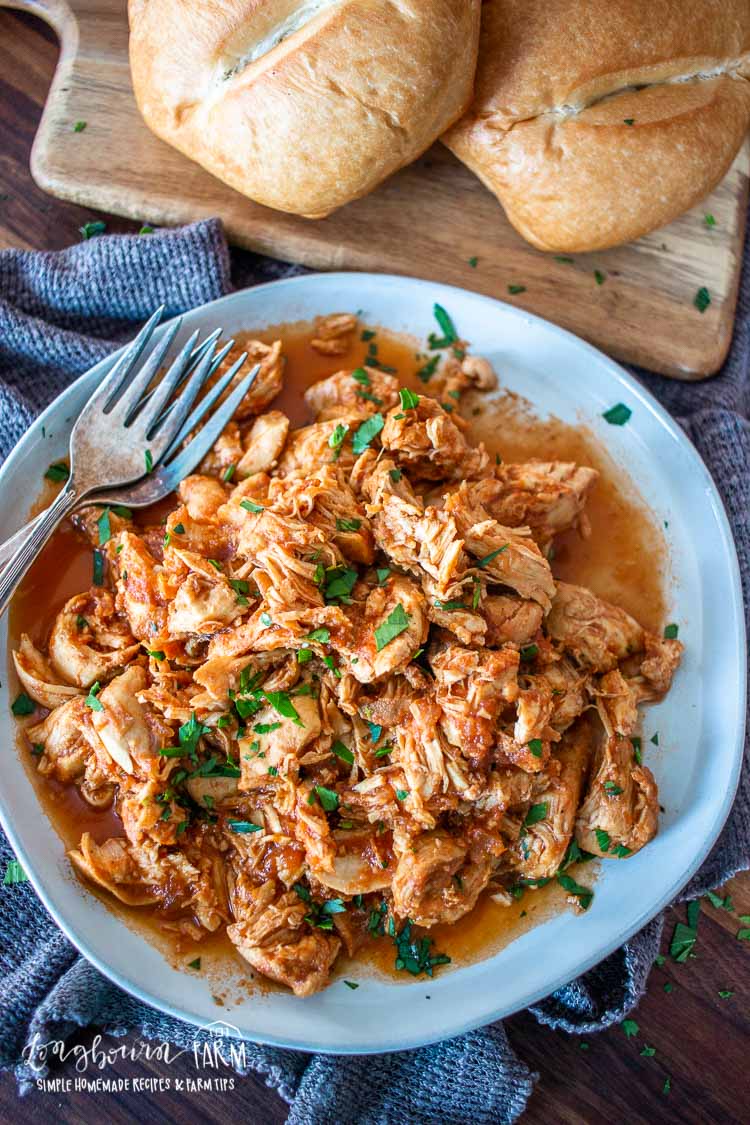 Instant pot bbq chicken on a light blue plate with forks.