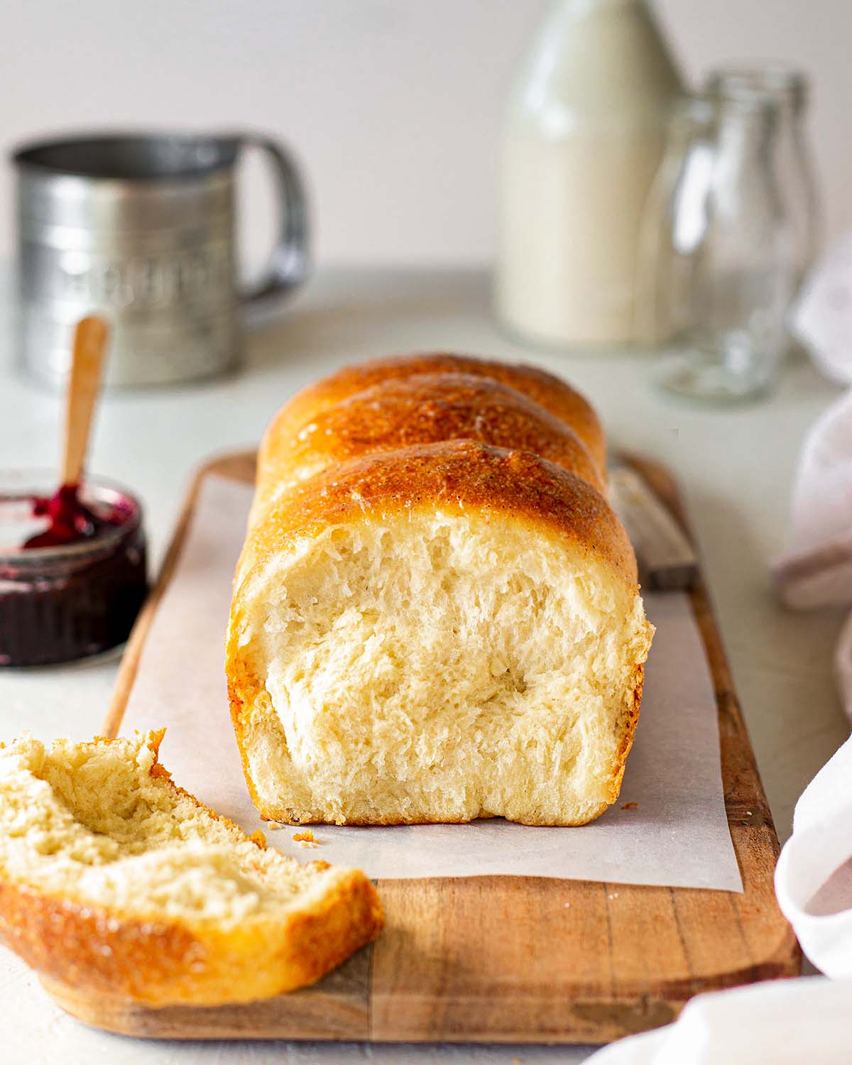 Vegan brioche bread on a wooden board with jam in the background.