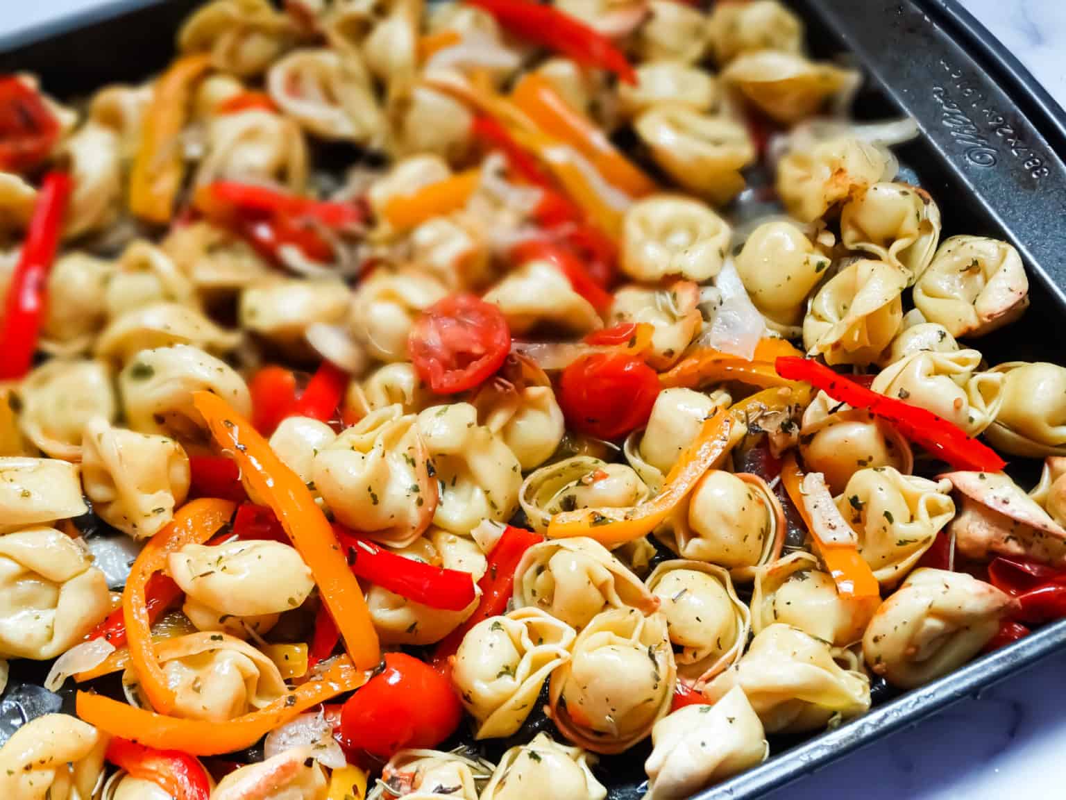 Roasted vegetable tortellini bake on a sheet pan.