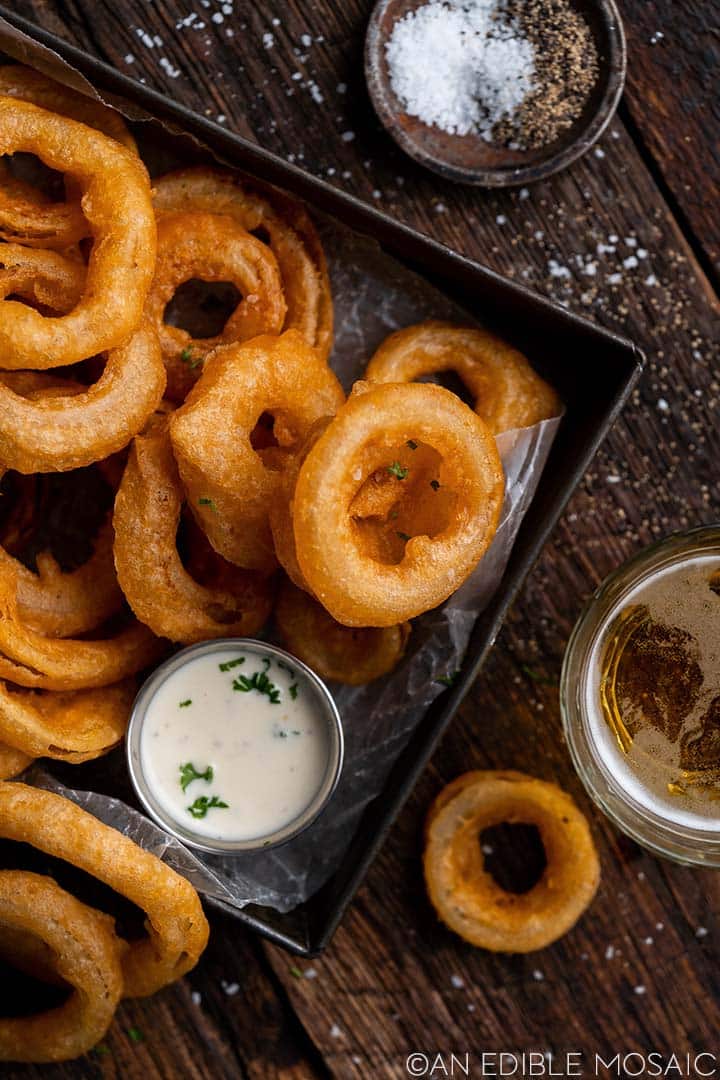 Beer batter onion rings in a square serving tray.