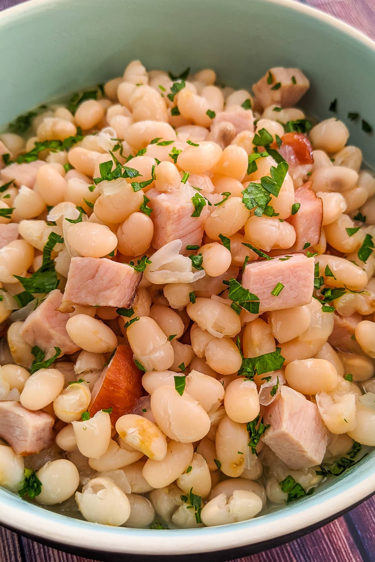 Old fashioned ham and beans stew in a blue bowl.