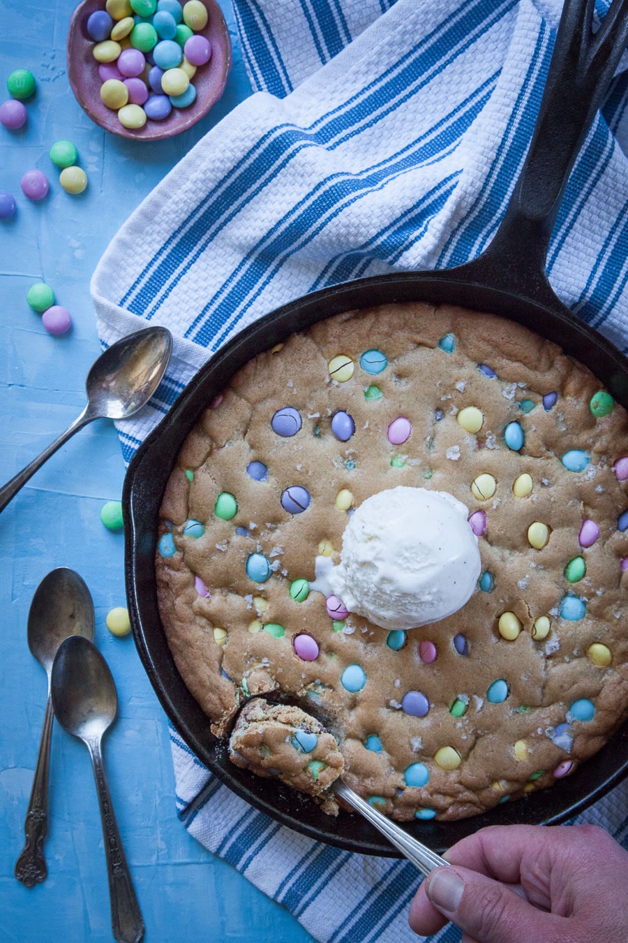 Giant cookie with M&Ms in a cast iron pan with a scoop of ice cream. 