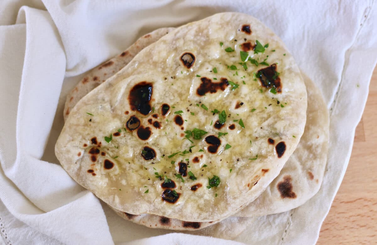 Stack of naan bread with butter and herbs.