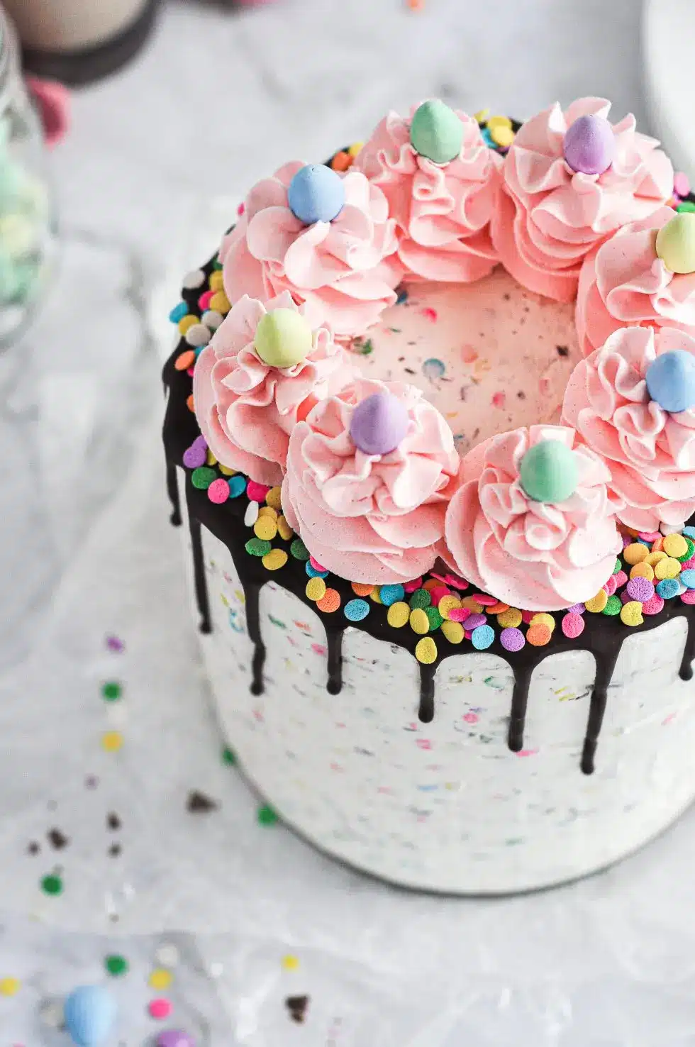 Pink mini egg cake decorated with mini eggs with chocolate dripped down sides.