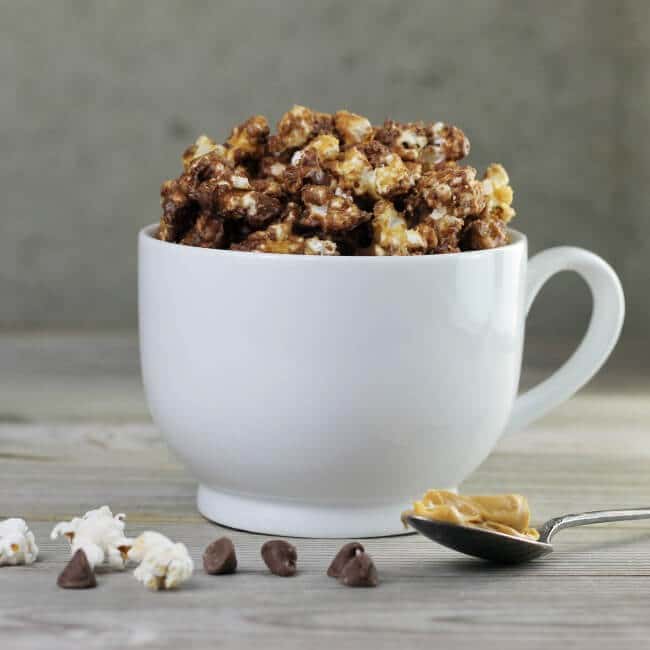 Chocolate peanut butter popcorn in white mug.