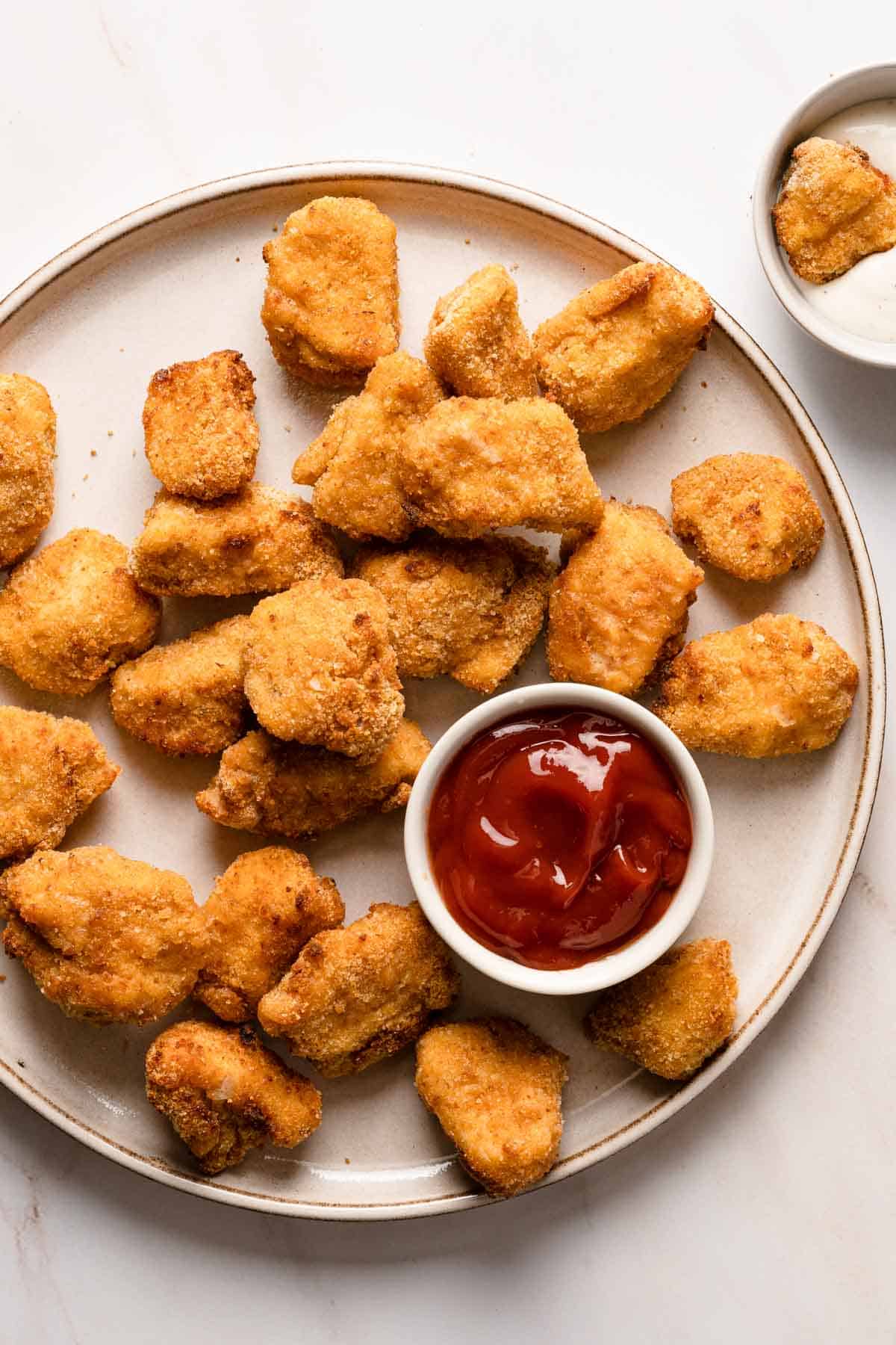 Air fryer chicken nuggets with ketchup on a plate.