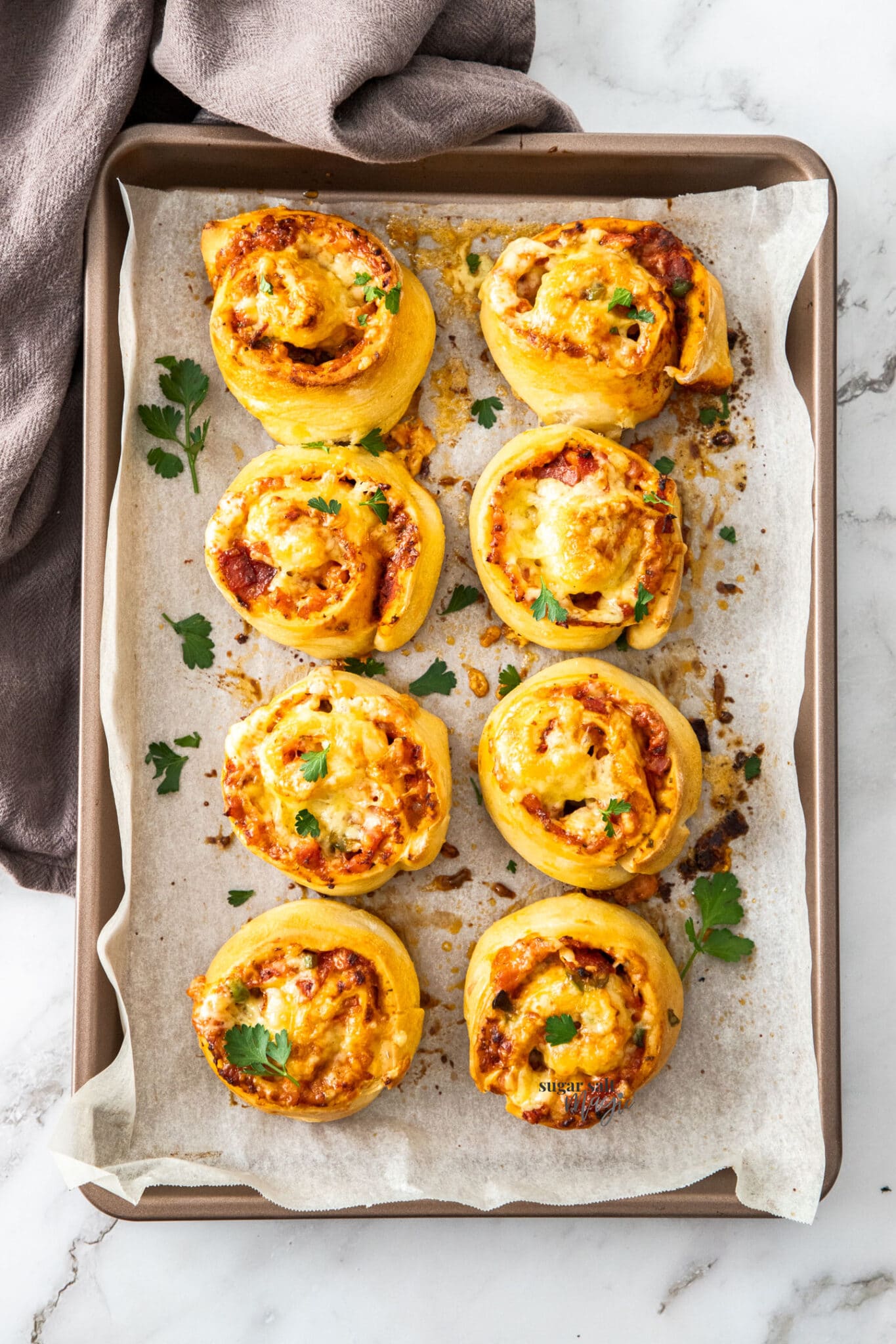 Pizza pinwheels on a parchment lined baking tray.