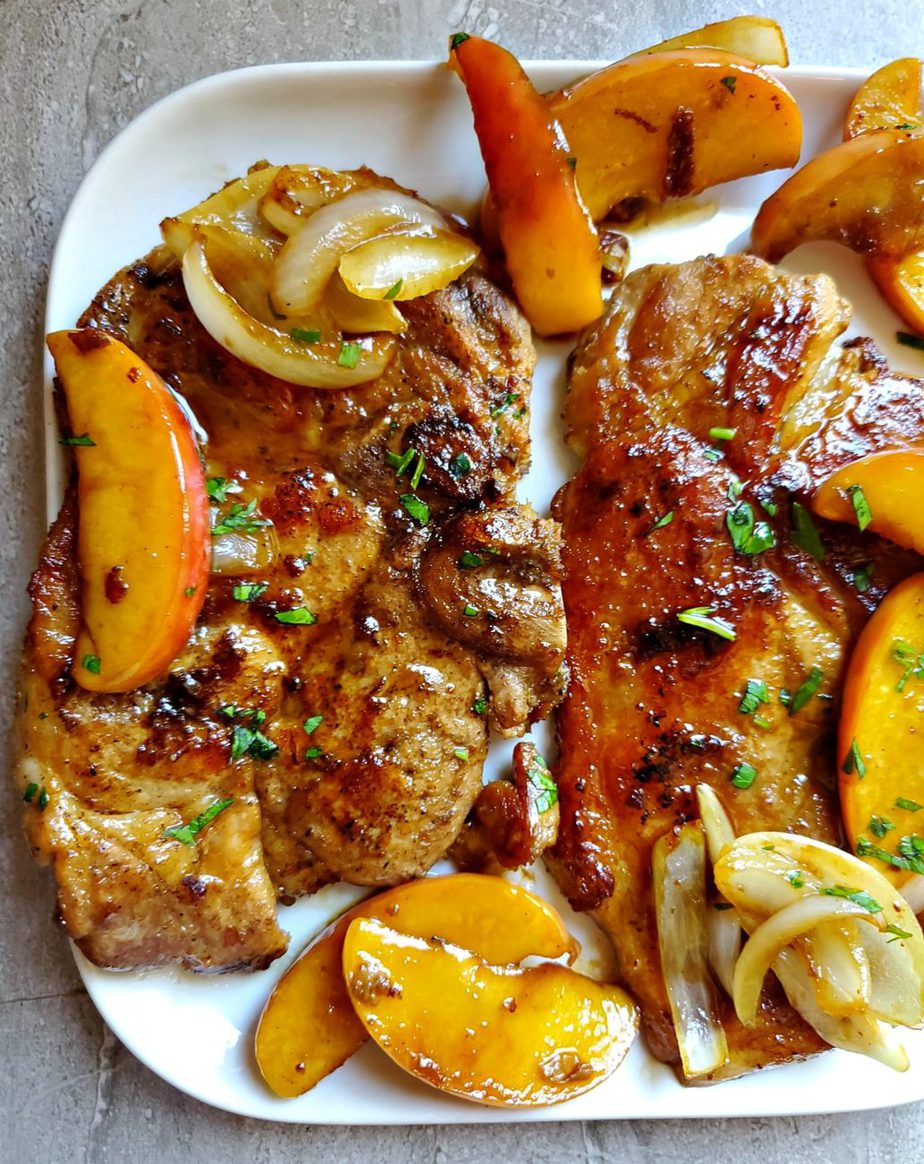 Pork chops with apples and maple syrup on a white dish.