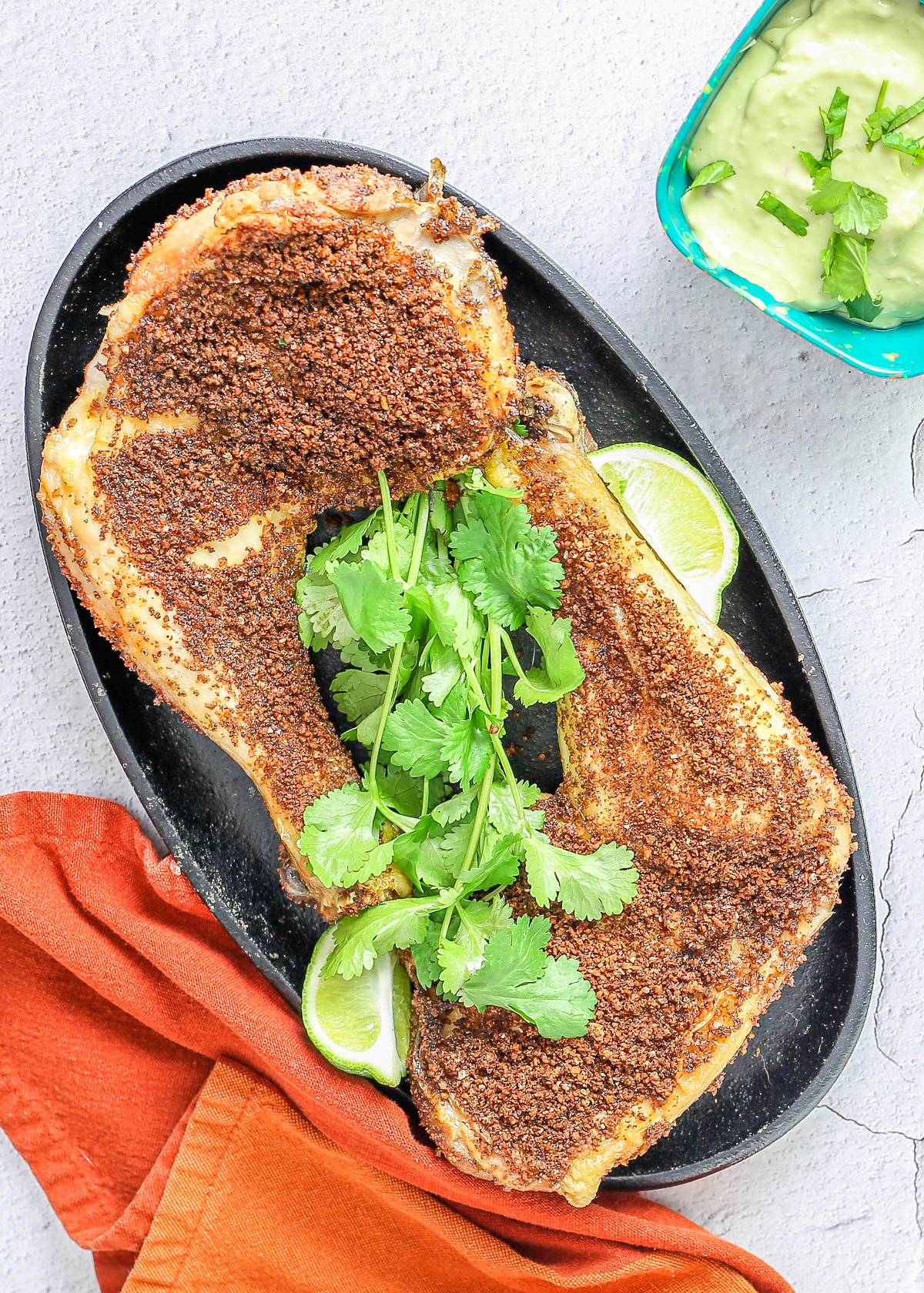 Mexican air fryer chicken leg quarters on a black plate.