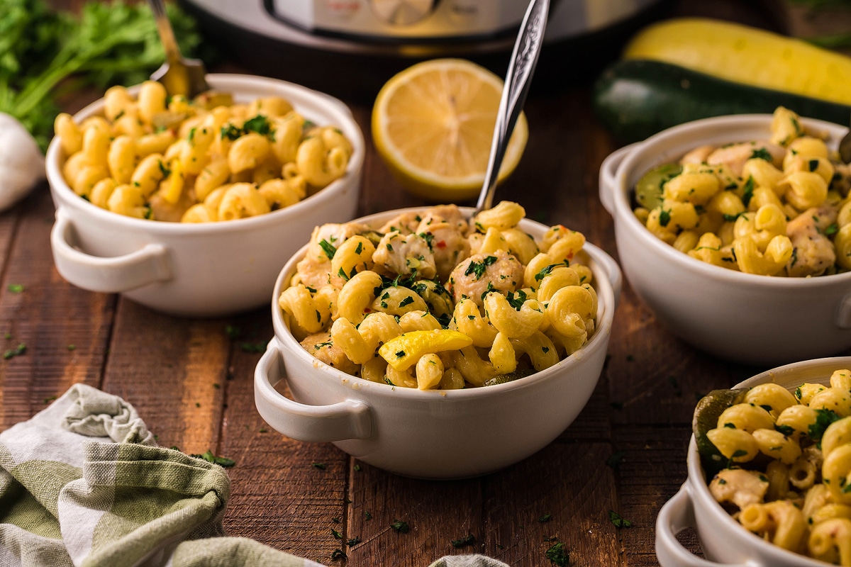 Buttery lemon chicken pasta with squash in a white serving bowl.