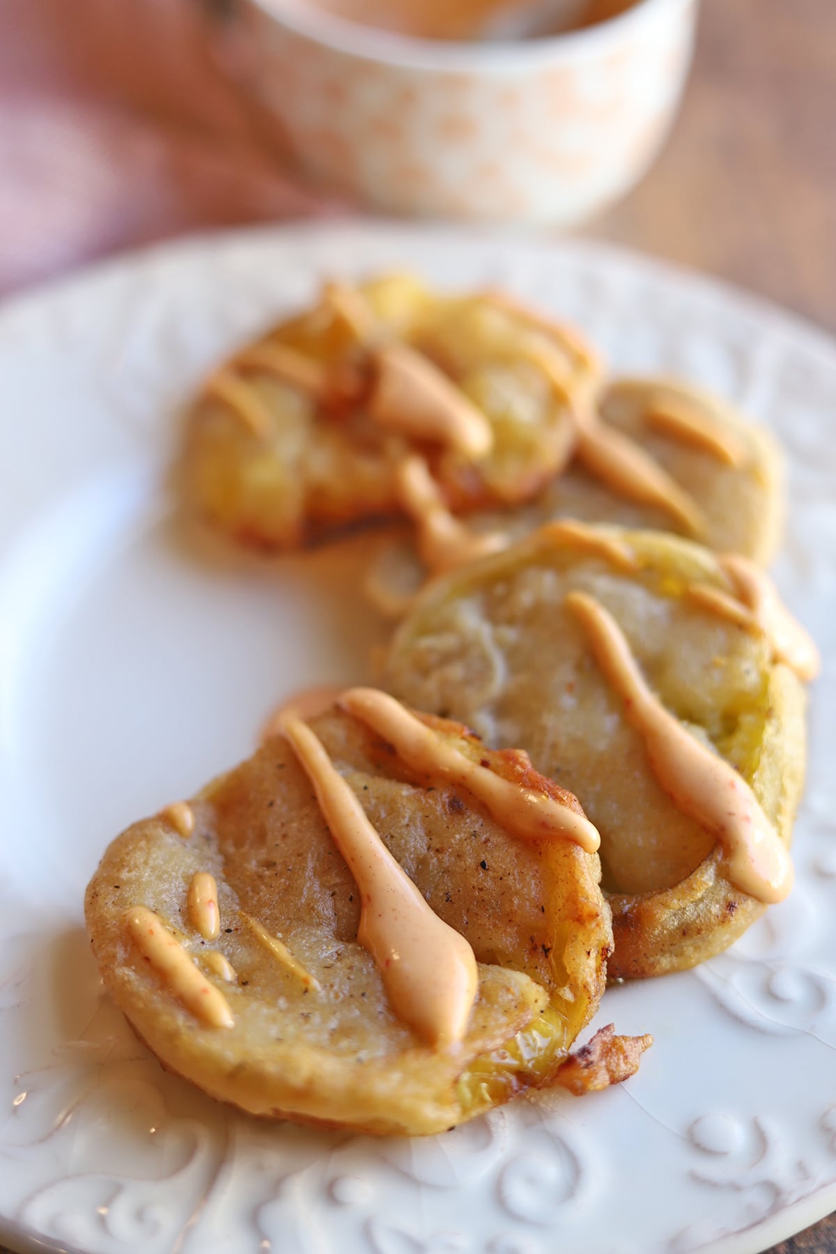 Fried green tomatoes with sauce on a white plate.