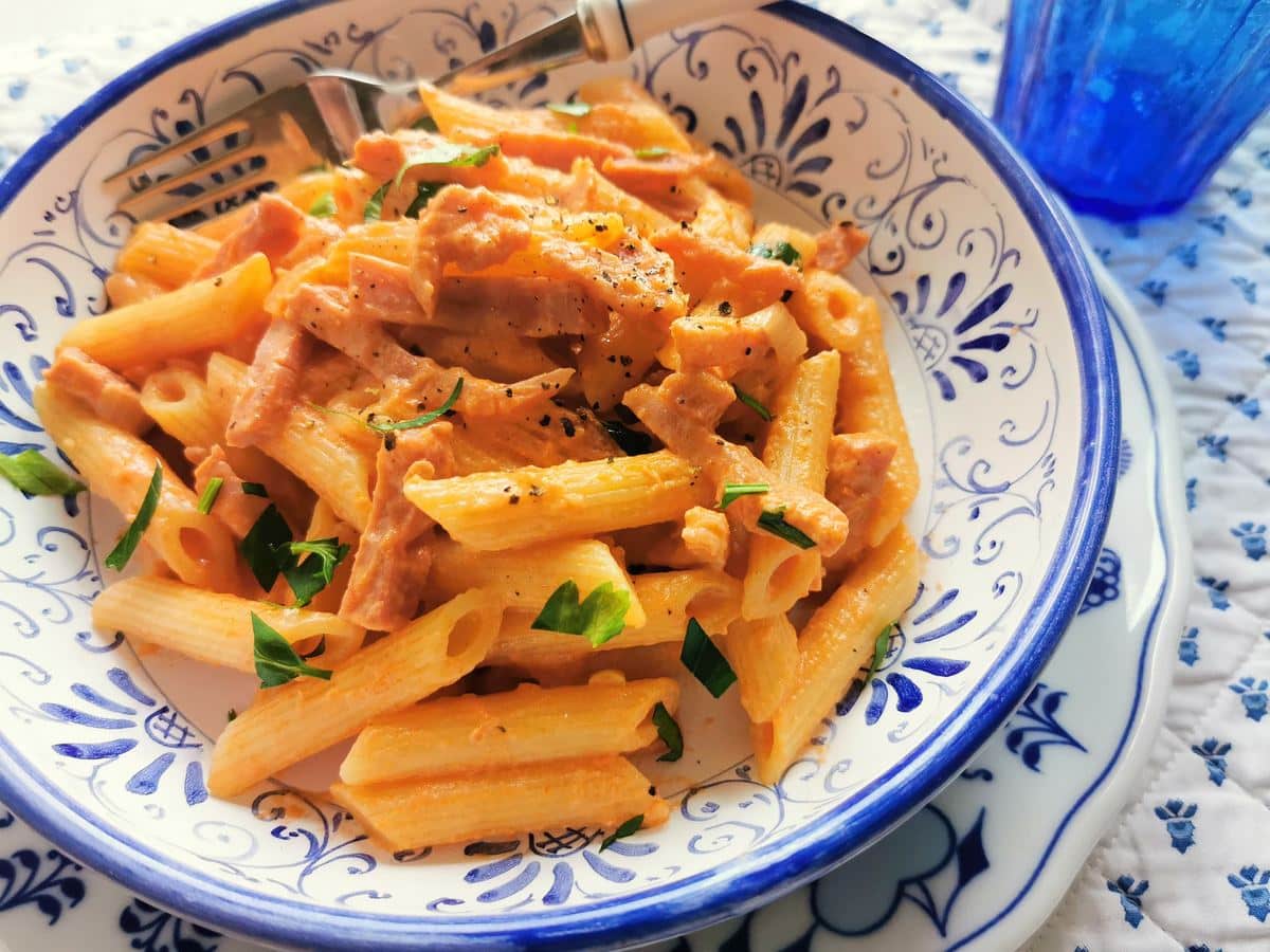 Creamy ham and tomato penne al baffo in a decorative bowl.