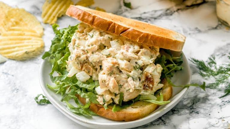 Rotisserie chicken salad with toasted bread and lettuce on a small white plate.