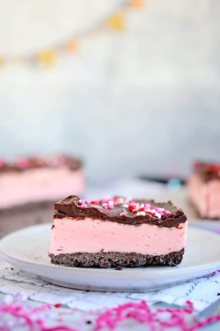 Slice of strawberry cheesecake on a white plate.