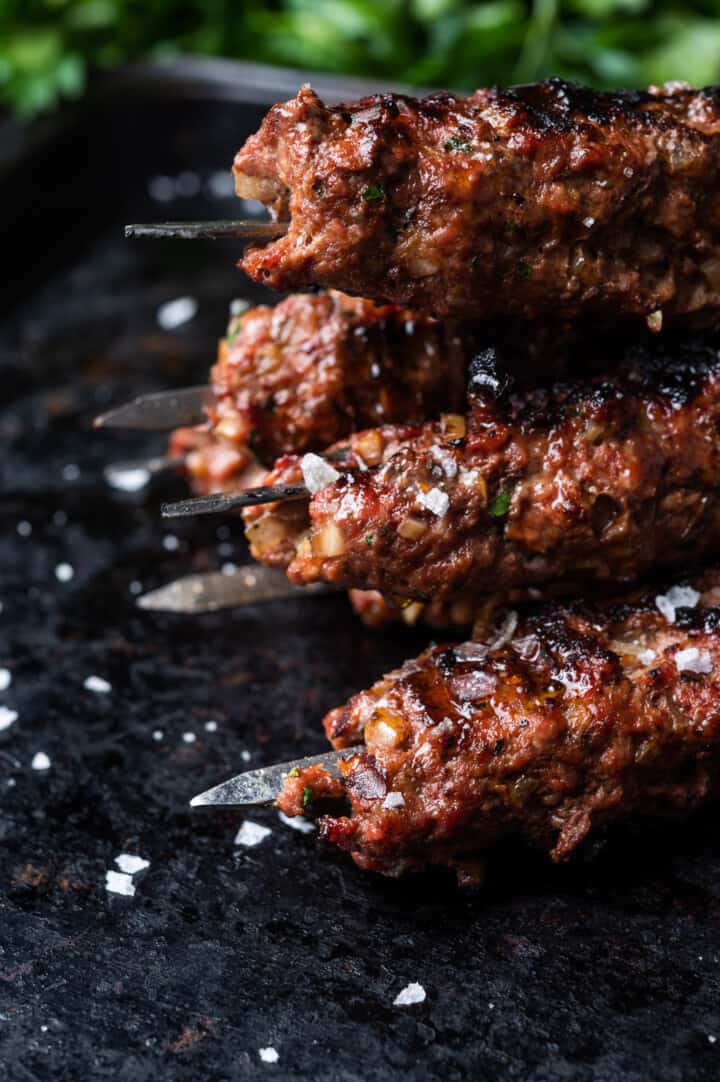 Ground meat kebabs on a dark surface.