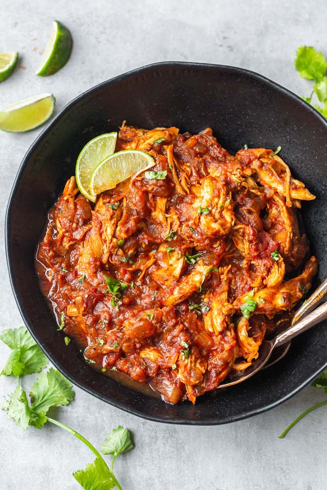 Instant Pot Chicken Tinga in black bowl with lime wedges.